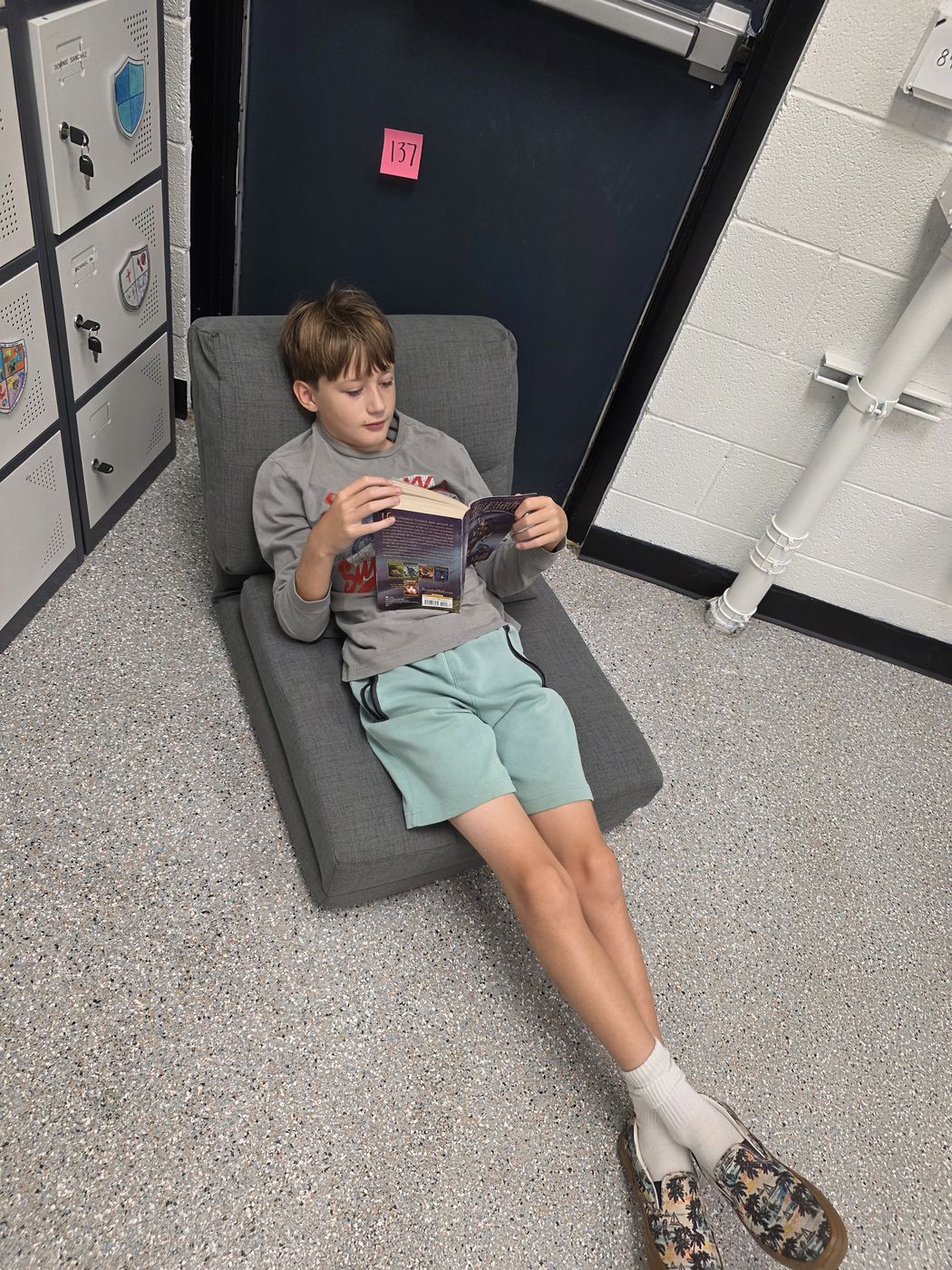 A student reading on a floor chair by the lockers